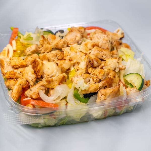 Grilled chicken salad with lettuce, tomatoes, cucumbers, and onions in a clear plastic container.