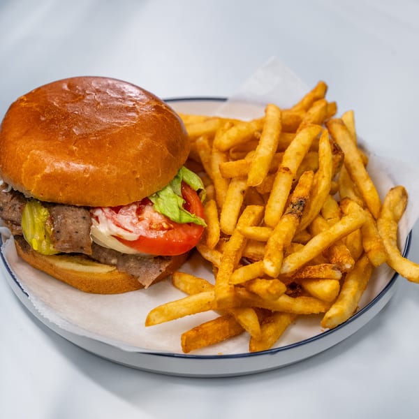 Sharks Fish & Chicken's beef burger with lettuce, tomato, onion, pickles, and a side of fries.