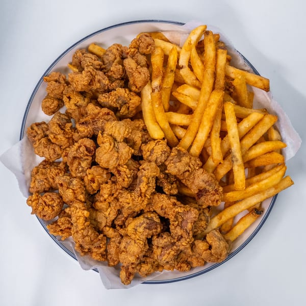 A white plate filled with golden-brown fried chicken pieces and crispy french fries.